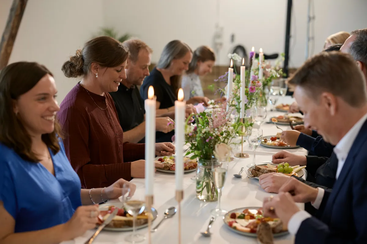 Selskab ved langbord med levende lys